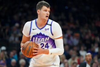 The newest Los Angeles Lakers player wearing his former team's uniform while holding the basketball tightly to protect it from his opponents