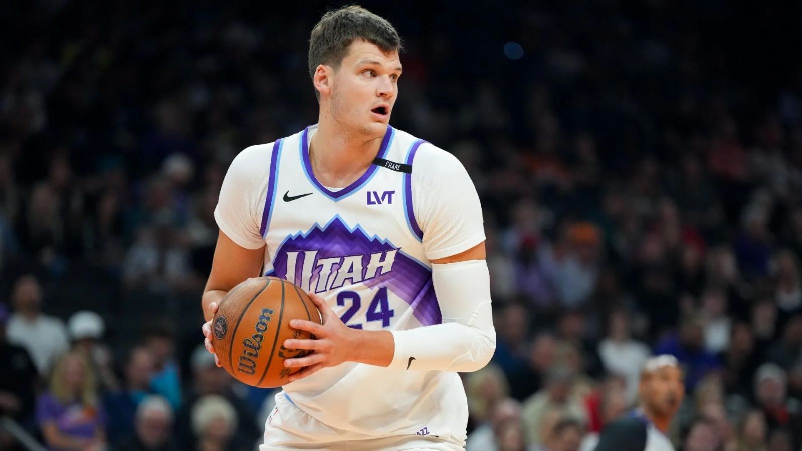 The newest Los Angeles Lakers player wearing his former team's uniform while holding the basketball tightly to protect it from his opponents
