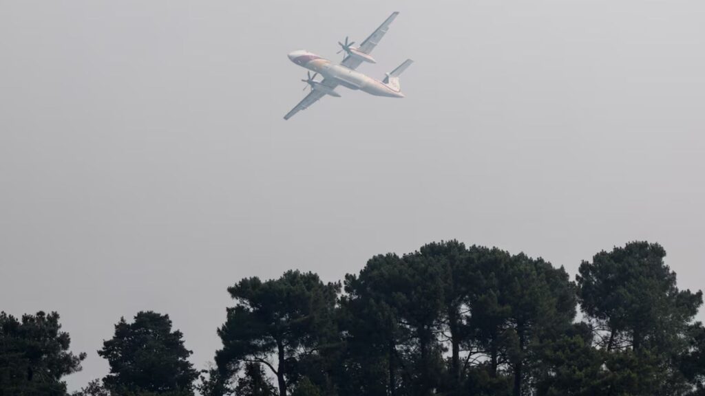 An aircraft flying over a forest engulfed in flames near Paris
