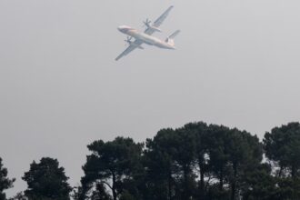 An aircraft flying over a forest engulfed in flames near Paris