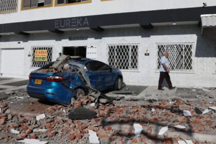 A car and a road covered in debris after several buildings and small houses collapsed in the city of Cali