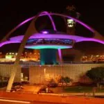 A giant main tower at Los Angeles International Airport with many lights illuminating the outside of the structure