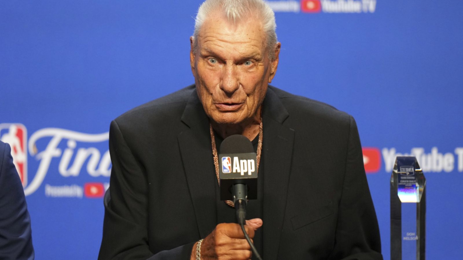 Don Nelson sitting in front of several microphones and speaking to everyone in attendance