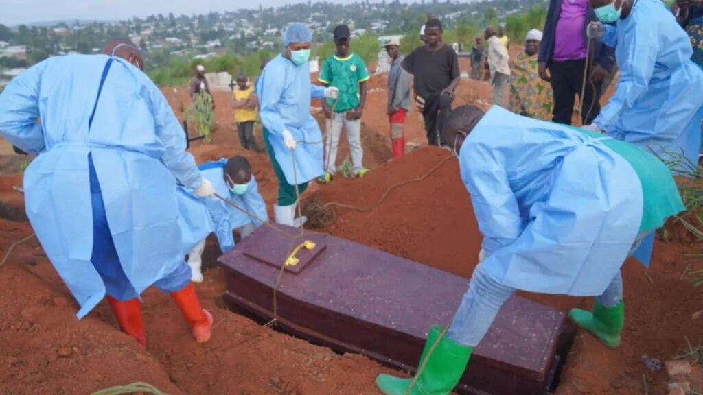 Several doctors burying multiple Ebola victims in a large field spanning many acres