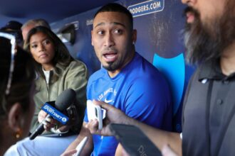 Díaz talking with several reporters on the bench at the Dodgers' training stadium