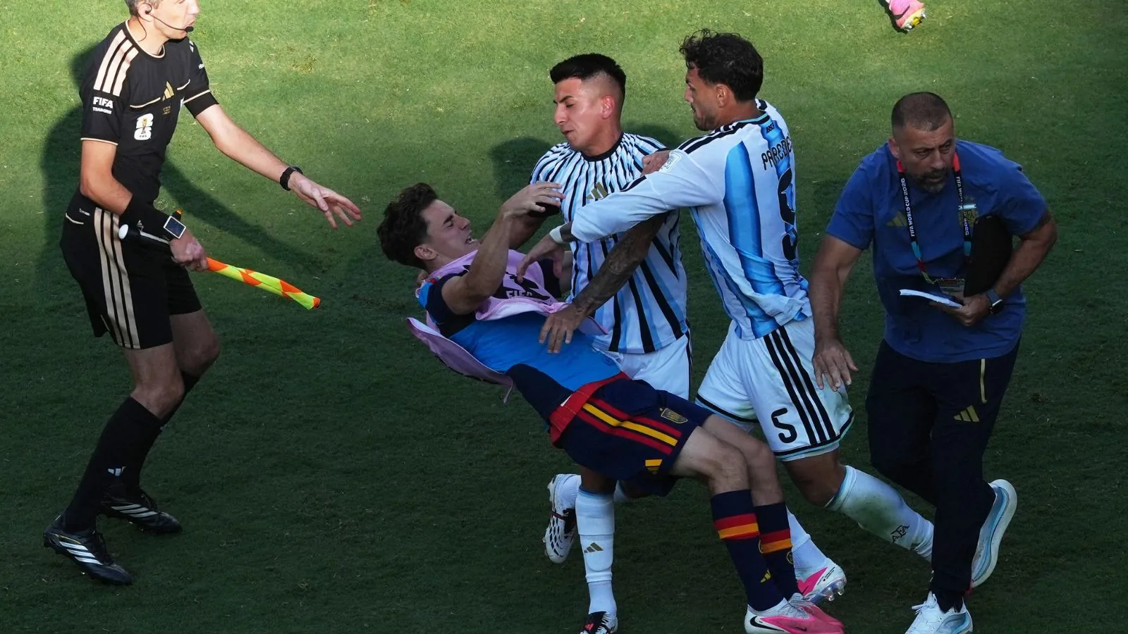 An Argentine player forcefully pushing a Spanish player, knocking him to the ground