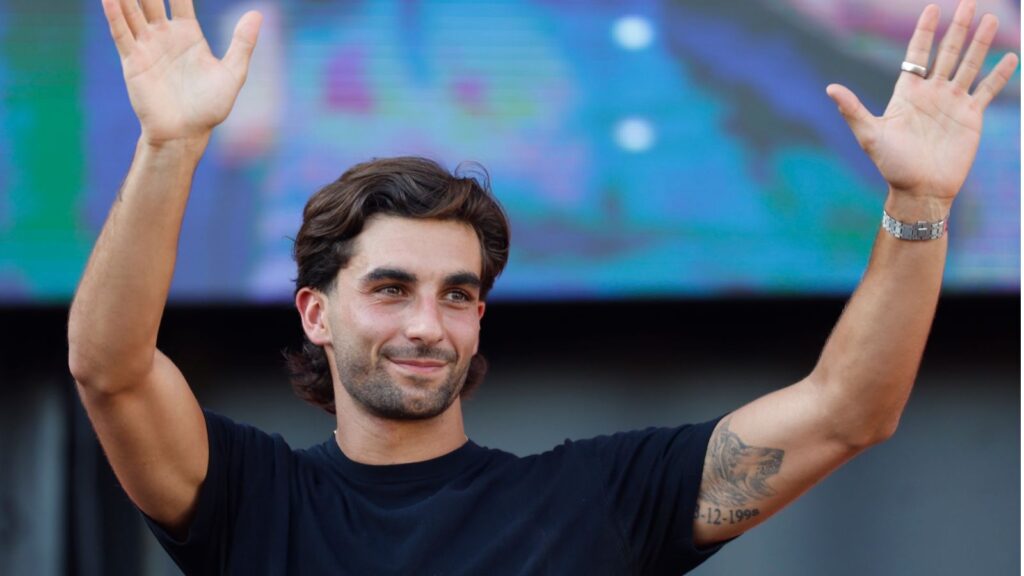 The Spanish player waving with both hands raised as he walks across the field