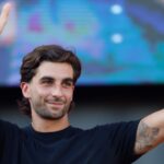The Spanish player waving with both hands raised as he walks across the field