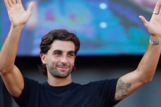 The Spanish player waving with both hands raised as he walks across the field