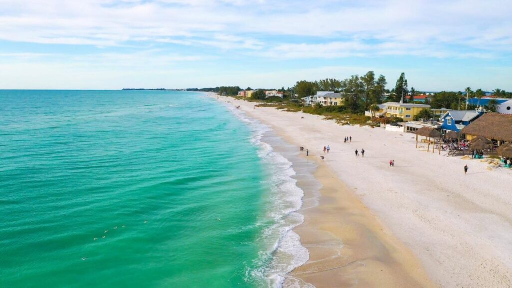 A beautiful Florida beach with crystal-clear blue water and several waterfront homes with direct beach access