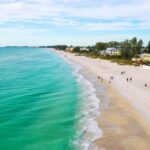 A beautiful Florida beach with crystal-clear blue water and several waterfront homes with direct beach access