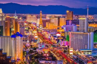 A view of Las Vegas with many cars and people on the streets, while the lights of its beautiful buildings remain illuminated