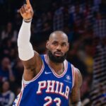 An image of the King wearing a Philadelphia jersey with the number 23, raising his hand after scoring a point
