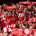 Many Liverpool fans at Anfield raising scarves and flags supporting their favorite team