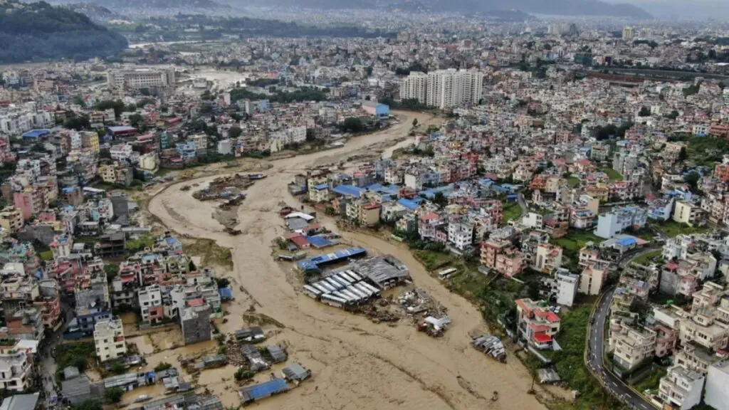 A city in Nepal with an overflowing river running completely through the city