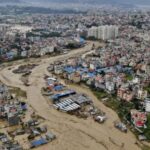 A city in Nepal with an overflowing river running completely through the city