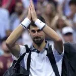 Novak clasping his hands in a gesture of respect and apology as he leaves the court