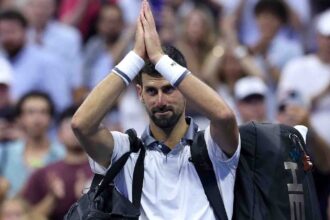 Novak clasping his hands in a gesture of respect and apology as he leaves the court