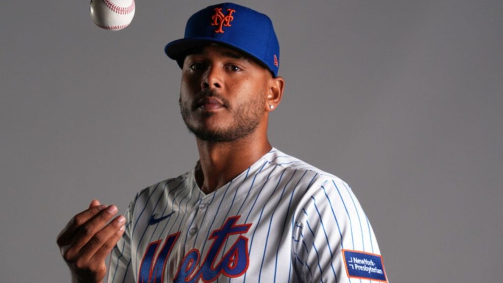 The player posing for the camera while gently tossing the baseball into the air