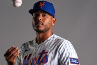 The player posing for the camera while gently tossing the baseball into the air