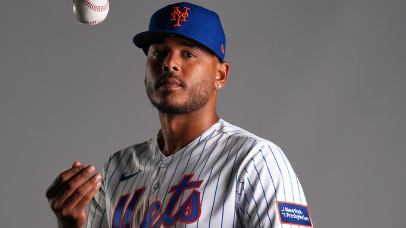 The player posing for the camera while gently tossing the baseball into the air