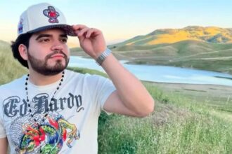 The influencer taking a photo of himself in a scenic landscape with mountains and a lake behind him