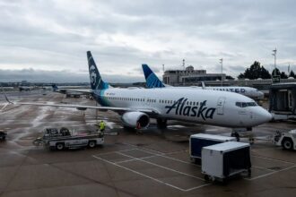 An Alaska Airlines plane being loaded with luggage before beginning its journey