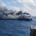 A large boat being engulfed in flames in the middle of the ocean