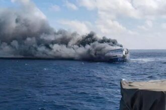 A large boat being engulfed in flames in the middle of the ocean