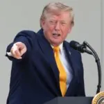 Trump renames Lake Ontario “Lake America” in new clash with Canada Trump pointing at someone in the audience while speaking into a microphone with a happy expression
