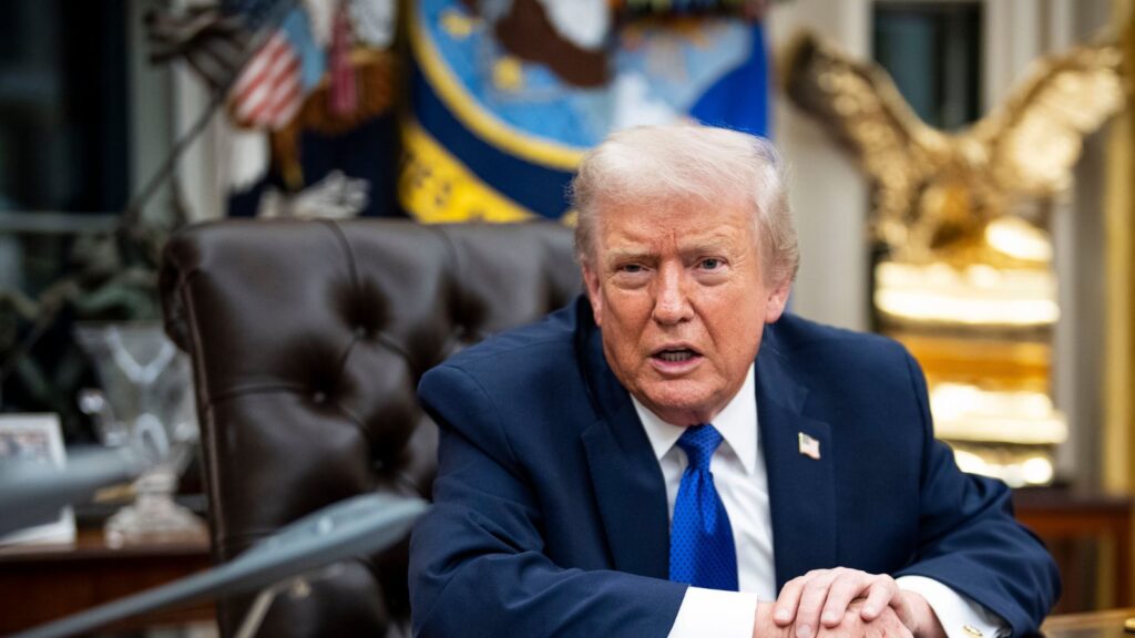 Trump sitting in his office while speaking with several people around him