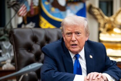 Trump sitting in his office while speaking with several people around him