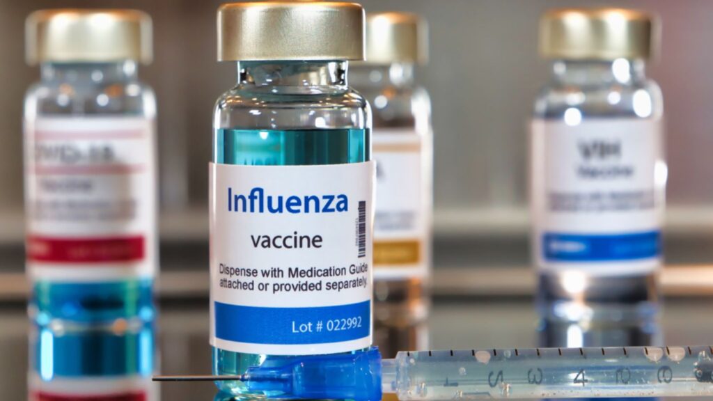 A table displaying several vials of influenza vaccine arranged neatly in a clinical setting