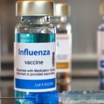 A table displaying several vials of influenza vaccine arranged neatly in a clinical setting