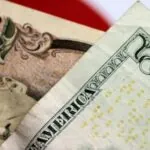 Two banknotes, one a 5-dollar bill and the other a 10,000-yen note, placed one on top of the other