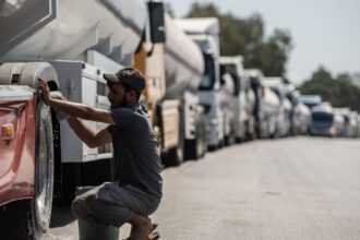 Fuel prices soar worldwide as protests erupt over rising energy costs A long line of tractor-trailers following road closures in Portugal