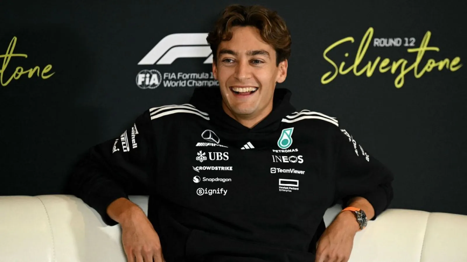 The Mercedes driver sitting on a couch and smiling at the cameras