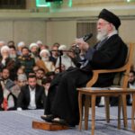 The leader of the Iranian regime sitting in a chair while surrounded by his followers