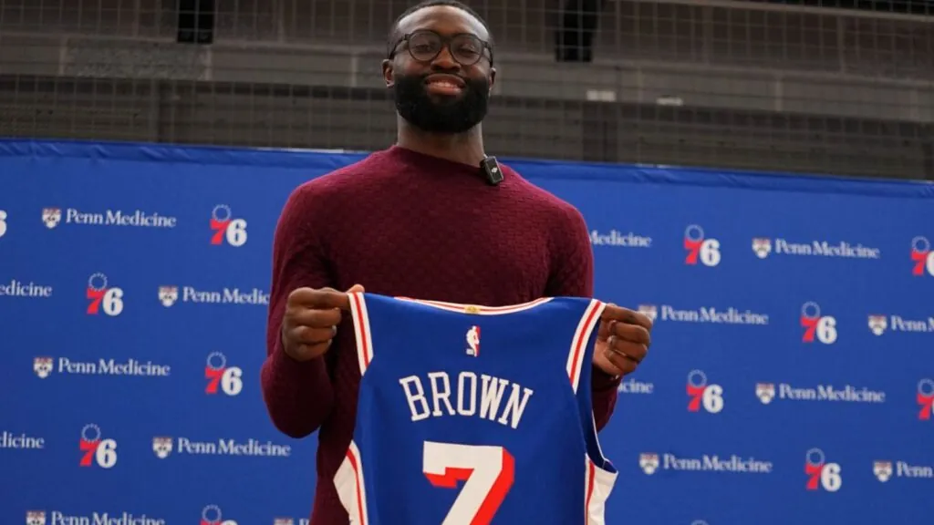 Jaylen Brown holding the Philadelphia jersey with the number 7 he will wear with the team