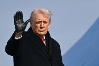 Trump wearing a brand-new suit with black gloves while waving to the crowd
