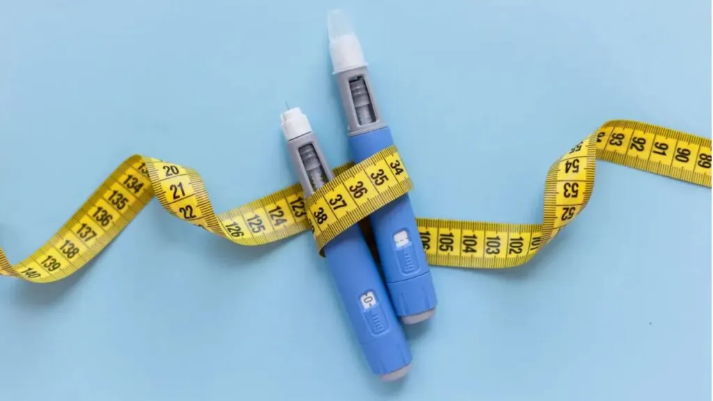 Two medication needles surrounded by a measuring tape symbolizing weight loss