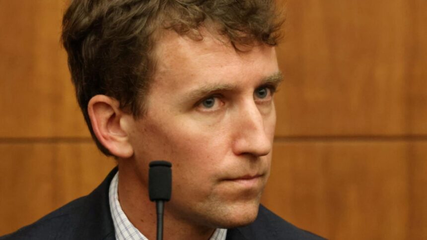 Patrick sitting in a courtroom, staring intently at the woman accused of killing his children