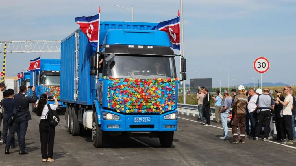 Russia and North Korea open historic first road bridge between the two countries Several blue trucks decorated with many flowers crossing the new bridge
