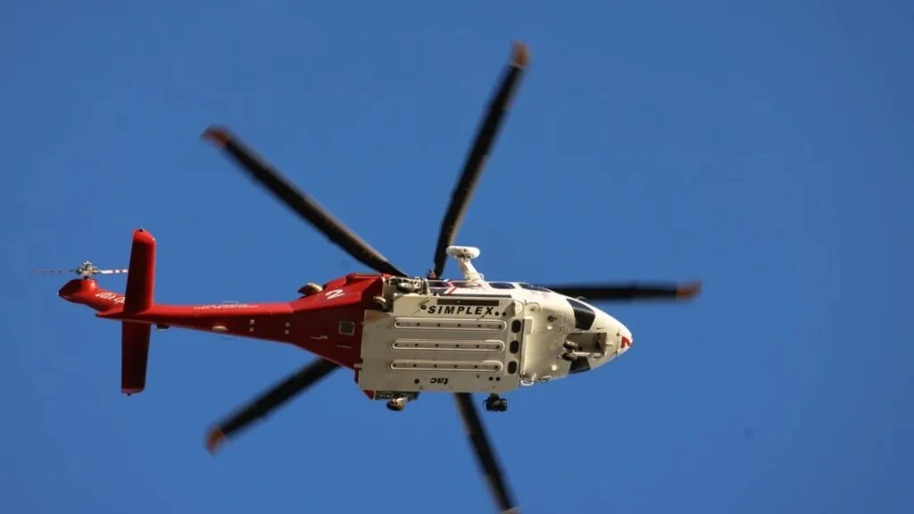 A white and red helicopter flying through the sky