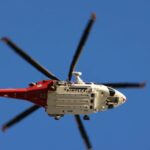 A white and red helicopter flying through the sky