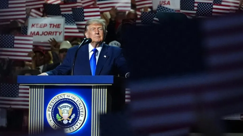 Donald Trump with a serious expression speaking into a microphone to his supporters