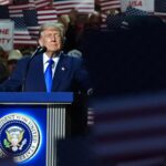 Trump promises $5,000 checks to american adults if republicans win Donald Trump with a serious expression speaking into a microphone to his supporters