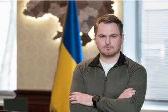 The young politician posing in a bedroom with a Ukrainian flag behind him